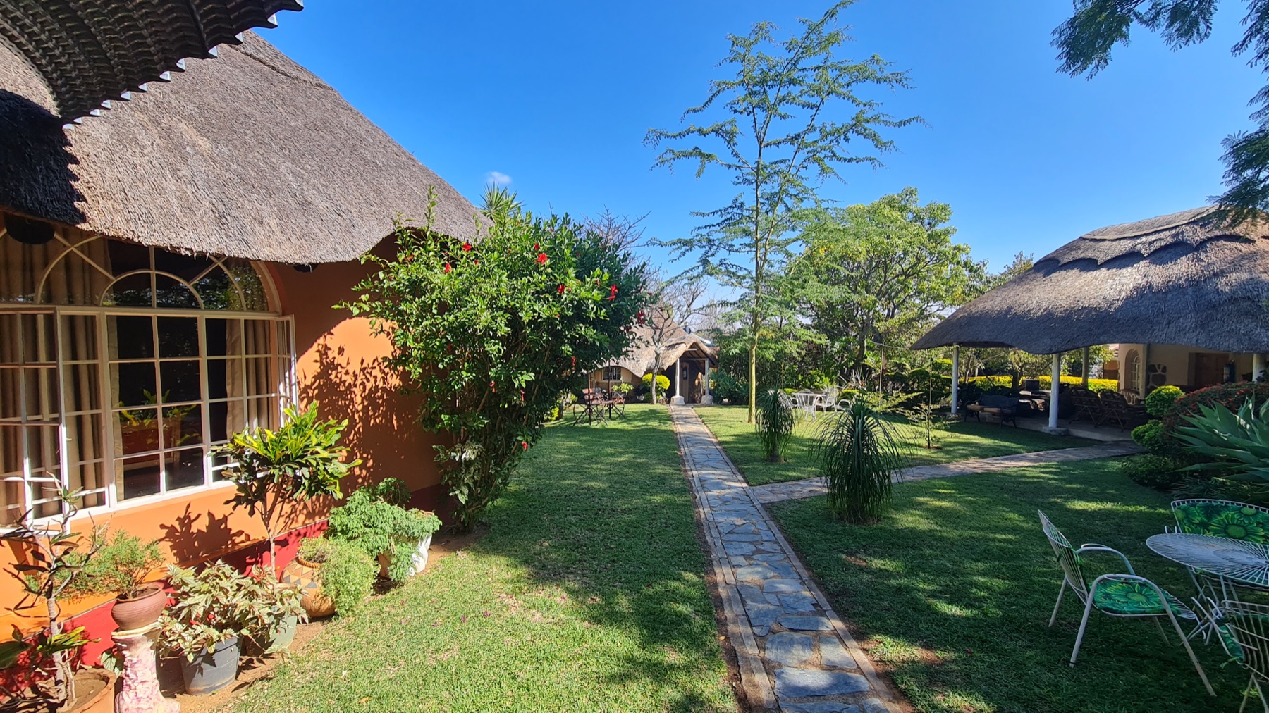 Garden courtyard with paths and thatched rooms at Lynn's Guesthouse
