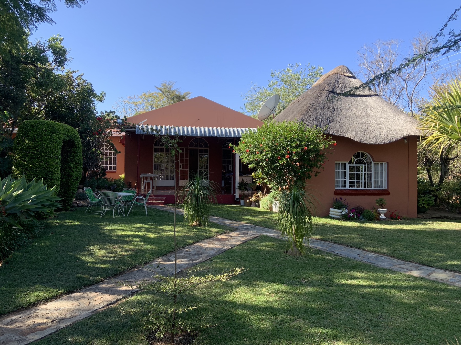 Garden and thatched rondavel exterior at Lynn's Guesthouse